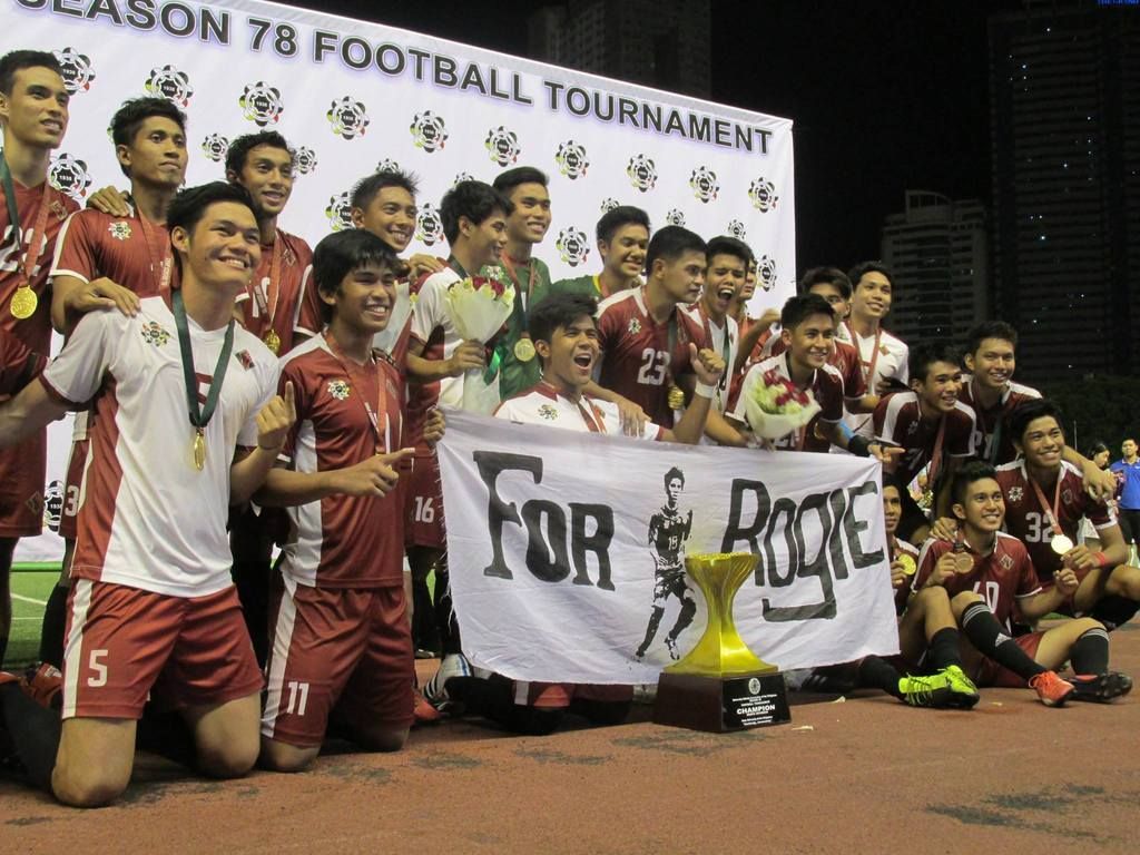 The members of the UP Men's Football Team hold a banner commemorating their fallen brother, Rogie Maglinas, after their win in the UAAP Season 78 Men's Football Tournament. Photo by David Tristan Yumol